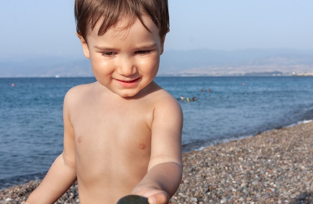 Mode de vie sain. Petit garçon se reposant et s'amusant sur une plage rocheuse sur la côte méditerranéenne