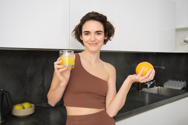 Mode de vie sain et sport belle femme souriante buvant du jus d'orange frais et tenant des fruits dans