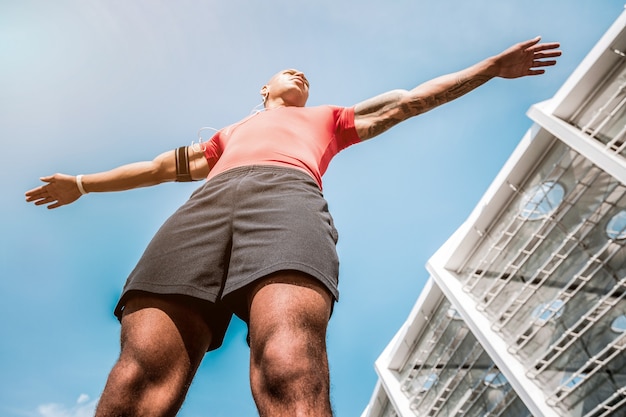 Mode de vie sportif. Faible angle d'un bel homme en forme debout près du stade