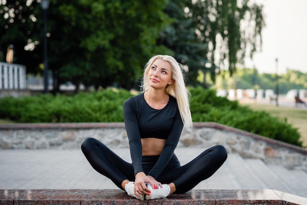 Mode de vie sportif sain. Belle jeune femme dans un vêtement de sport s'asseoir dans le parc de la ville