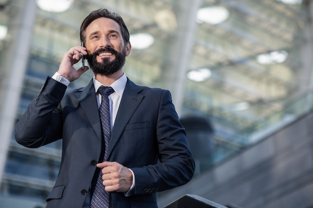 Mode de vie urbain. Taille d'un homme d'affaires barbu positif ayant une conversation téléphonique