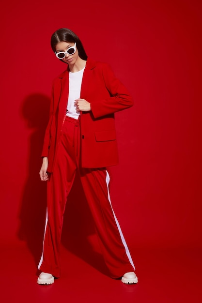 Modèle asiatique en costume rouge, bottes blanches et lunettes de soleil