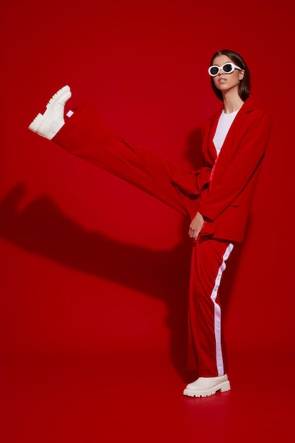 Modèle asiatique en costume rouge, bottes blanches et lunettes de soleil