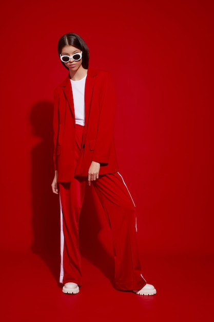 Modèle asiatique en costume rouge, bottes blanches et lunettes de soleil