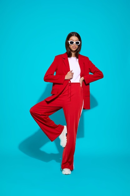 Modèle asiatique en costume rouge, bottes blanches et lunettes de soleil