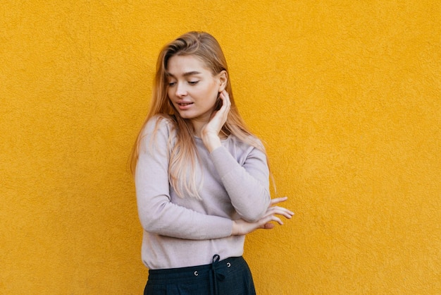 Modèle attrayant et élégant de jeune fille posant sur un fond de mur jaune