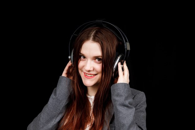 Modèle aux cheveux noirs pose dans un studio sombre avec un casque sur la tête