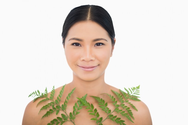 Modèle aux cheveux sombre sensuel posant avec fougère