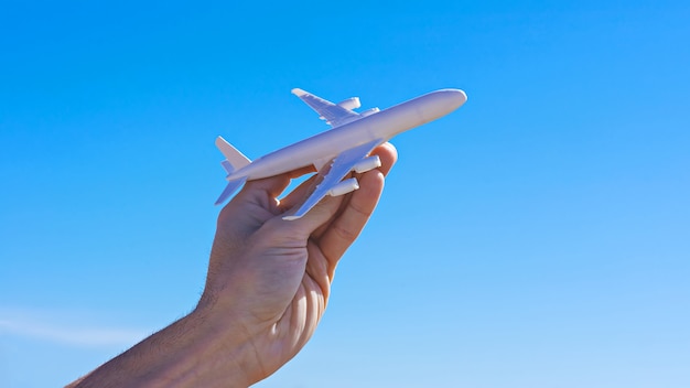 Modèle d'avion en main contre un ciel bleu clair