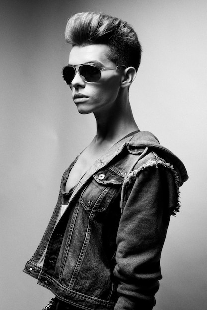 Modèle de beau jeune homme avec coupe de cheveux de mode et lunettes de soleil