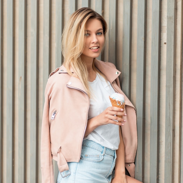 Modèle de belle femme heureuse avec un sourire dans une veste rose à la mode avec une glace savoureuse