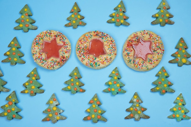 Modèle de biscuits faits maison de Noël disposés en rangées sur un fond bleu orientation horizontale