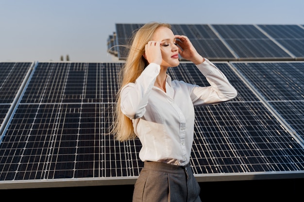 Modèle blonde avec des panneaux solaires se dresse en ligne sur le sol