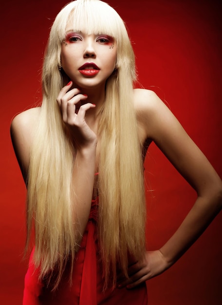 Photo modèle blonde parfaite en robe rouge sur fond rouge