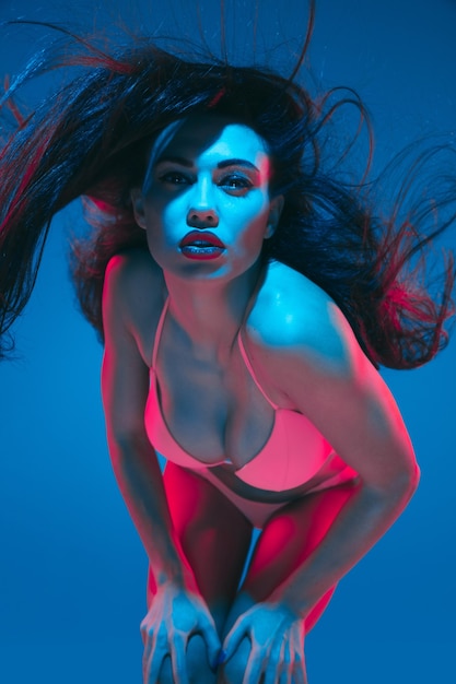 Photo modèle brune attrayante sur fond bleu studio en néon