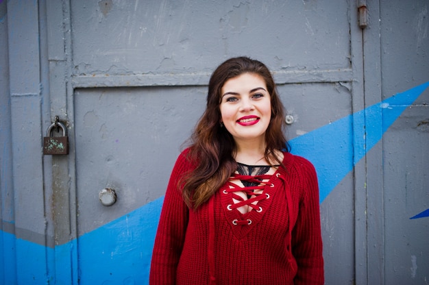 Modèle brune au rouge contre le mur coloré.