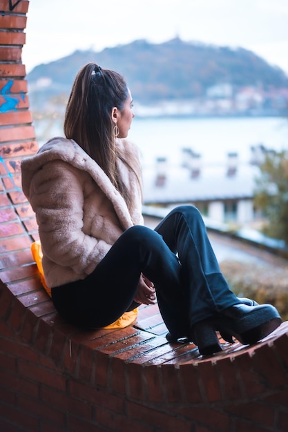 Modèle brune caucasienne assis en hiver en regardant la mode de style de rue de la ville