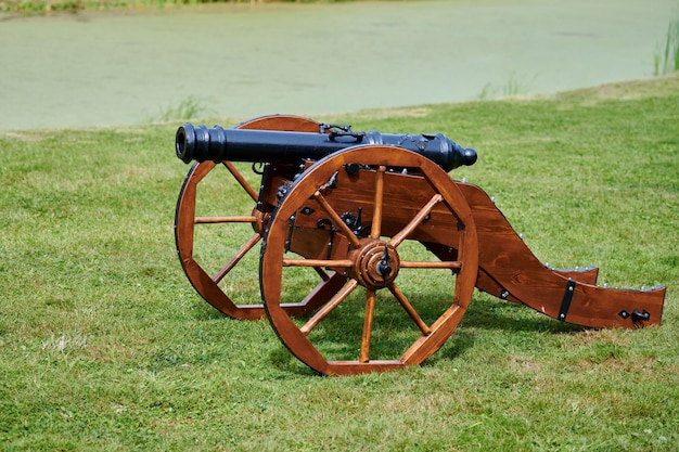 Modèle de canon restauré pour la défense du château, fond de pelouse verte. Canon d'artillerie de gros calibre, vieux canon antique sur roues en bois. Protéger contre l'attaque de l'ennemi, reconstitution historique de la guerre civile