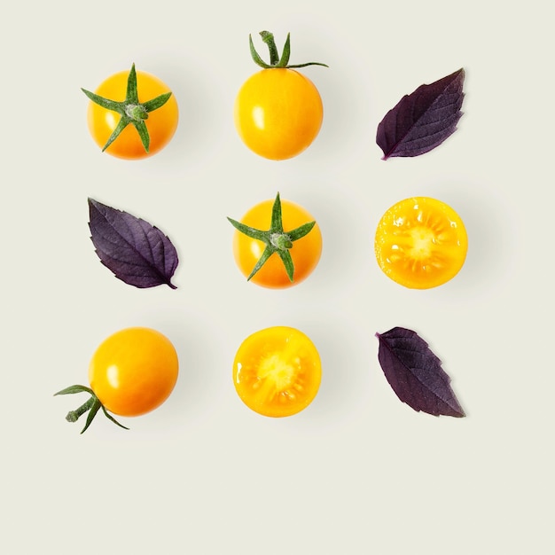 Modèle carré de tomates cerises jaunes et de feuilles de basilic violet sur fond gris clair