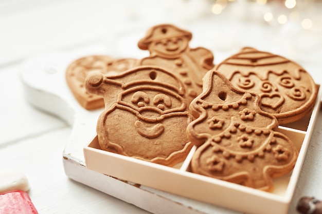 Modèle de carte postale de Noël. Biscuits de pain d'épice sur tableau blanc. Flocon de neige, père Noël, homme, formes de bonbons. Biscuits de Noël sur une table en bois blanche. Biscuits de Noël avec décoration festive