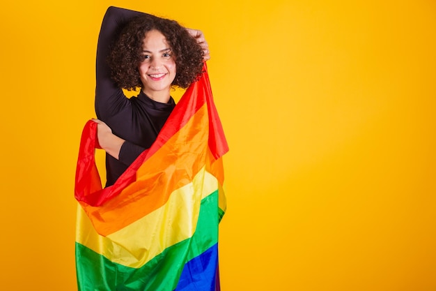 Modèle caucasienne avec une chemise noire et des jeans bleus avec un arc-en-ciel de drapeau LGBT