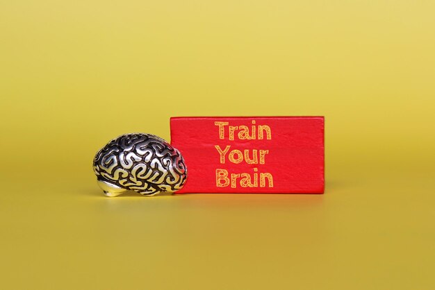 Modèle de cerveau et cube en bois rouge avec texte Entraînez votre cerveau sur fond jaune