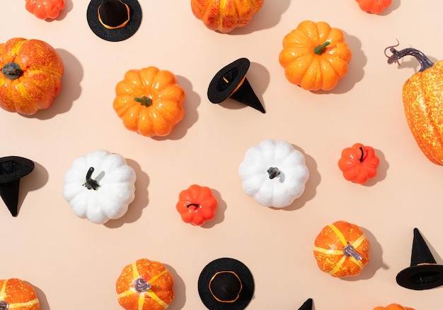 Modèle de citrouilles artificielles colorées et de chapeaux d'halloween sur fond orange