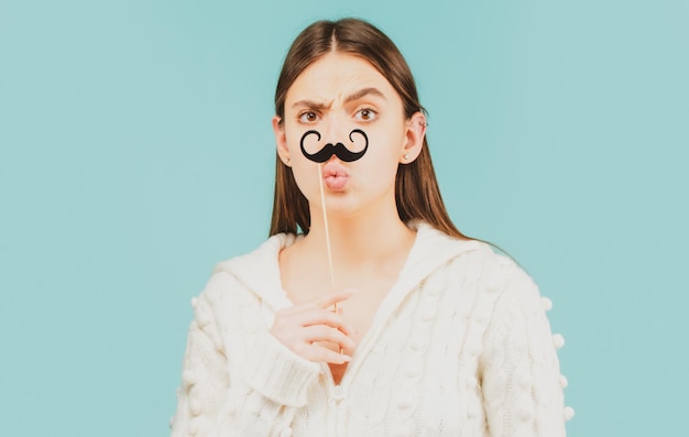 Modèle de clin d'œil surpris Fille tenant une moustache drôle sur un bâton et montrant un espace de copie vide sur la paume de la main ouverte pour le texte fond blanc Fille présentant le point Proposer un produit Geste publicitaire