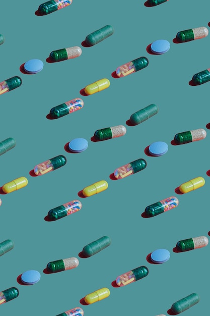 Modèle coloré vibrant de capsules et de comprimés de pilule de médecine sur le fond vert. Concept créatif d'utilisation de médicaments surdosés et de dépendance aux compléments alimentaires.