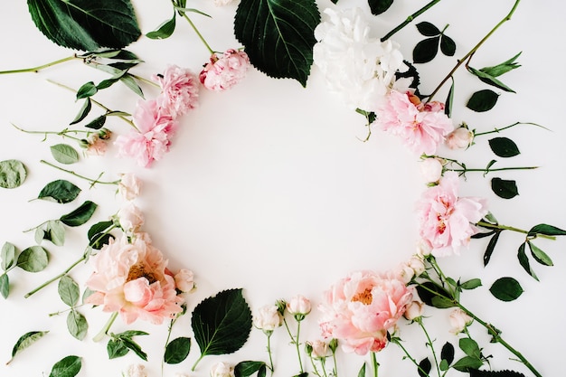 Modèle de couronne de cadre rond avec des roses, des pivoines, des branches et des feuilles isolées sur blanc