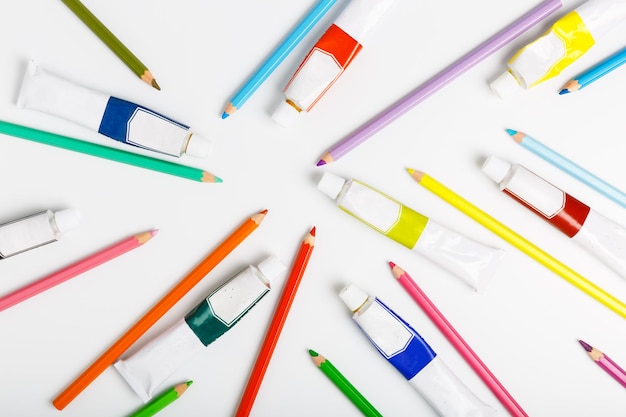Modèle de crayons de couleur et de tubes avec de la peinture à l'huile sur fond blanc Concept de magasin d'art ou d'école de dessin mise à plat Vue de dessus