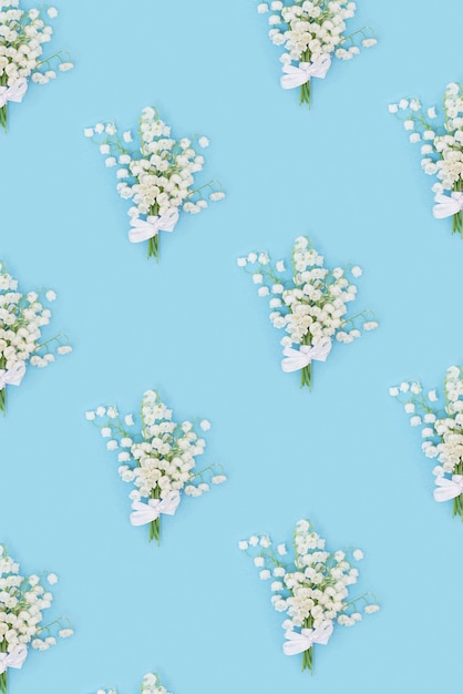 Modèle créatif avec des fleurs de printemps des muguets blancs sur fond bleu pastel