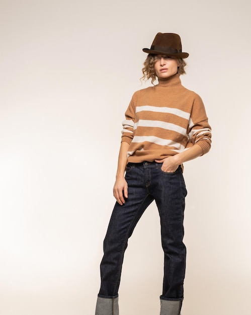 Un modèle dans un pull marron à rayures et un jean