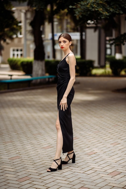 un modèle dans une robe noire est debout sur une passerelle en brique