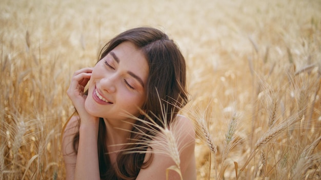 Modèle d'été appréciant le temps venteux rye meadow gros plan femme satisfaite se reposant