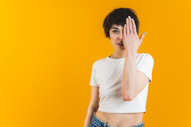 Modèle féminin avec des lèvres légèrement entrouvertes et une main posée sur son œil fond orange