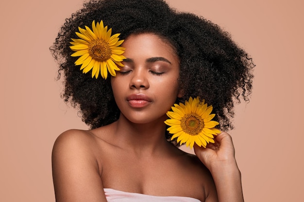 Modèle féminin noir décorant les cheveux avec des fleurs