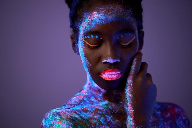 Modèle féminin noir sexuel posant avec un motif uv sur le corps maquillage d'art corporel fluorescent calme calme b ...