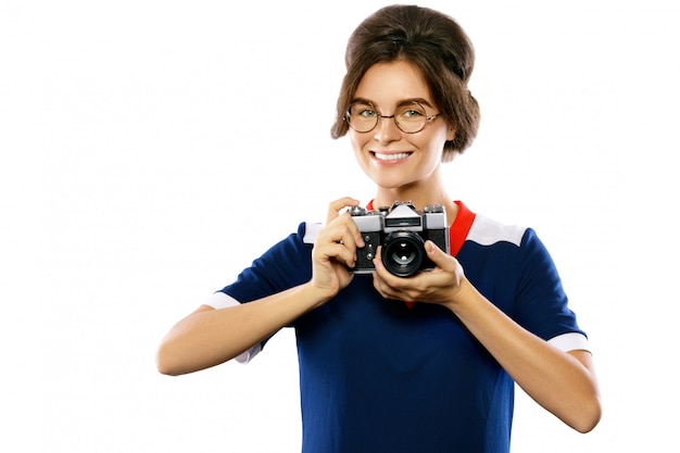 Modèle femme au look vintage tenant un appareil photo rétro dans ses mains