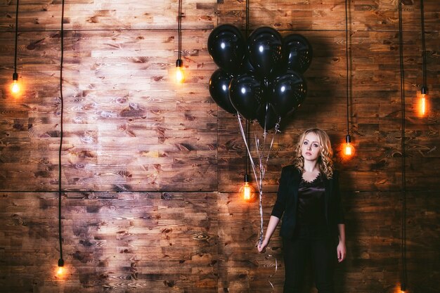 Modèle femme belle et à la mode sur le fond d'un mur en bois avec ballon d'éclairage horizontal