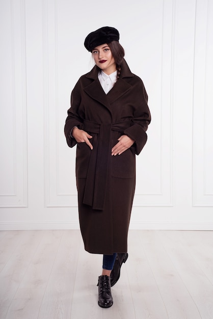 Modèle de fille brune dans un long manteau marron. pose