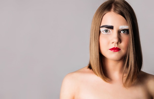 Modèle fille avec une coupe courte et des sourcils noirs et blancs.