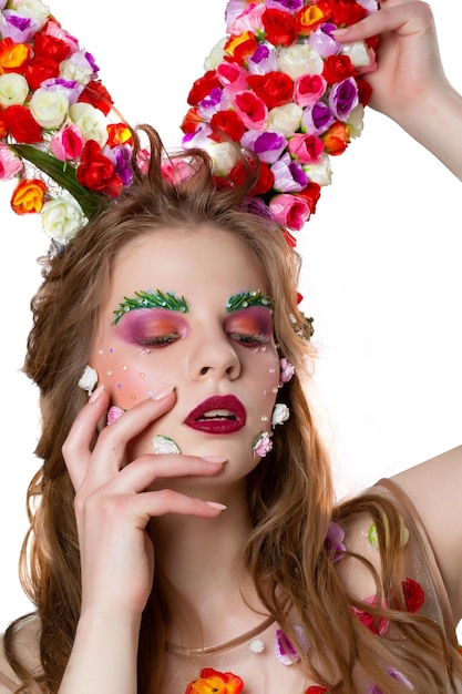 Modèle de fille de printemps de conte de fées avec des cornes florales et un maquillage lumineux sur fond blanc