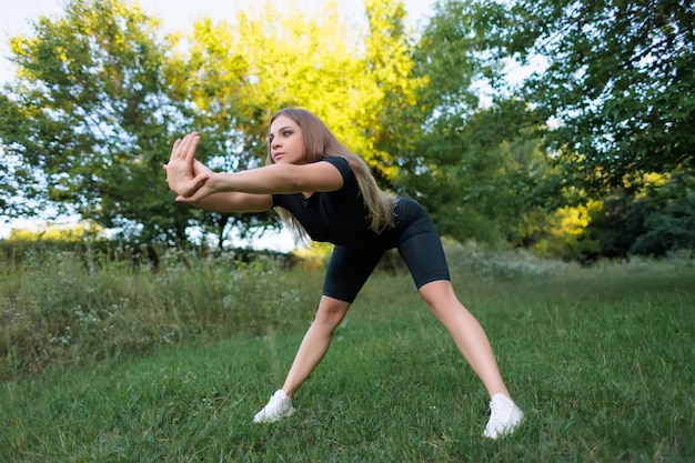 Le modèle de fitness fait du sport dans le parc en plein air en se penchant en avant