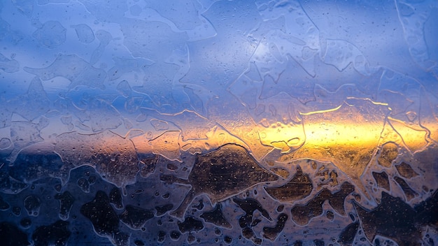 Modèle givré hivernal sur fond abstrait de verre de fenêtre gelée de glace soleil d'hiver brille à travers le verre dépoli sur la fenêtre