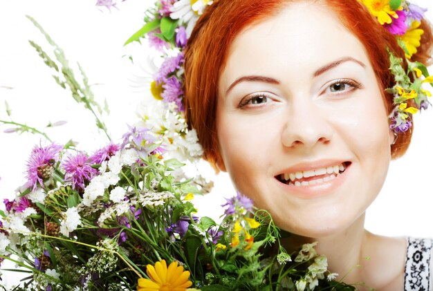 Modèle avec une grande coiffure et des fleurs dans les cheveux et avec des fleurs en bouquet.