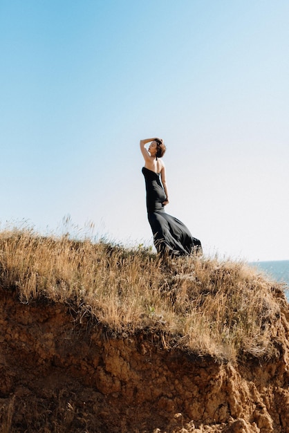 Modèle de grande fille dans une robe noire sur les collines de la montagne