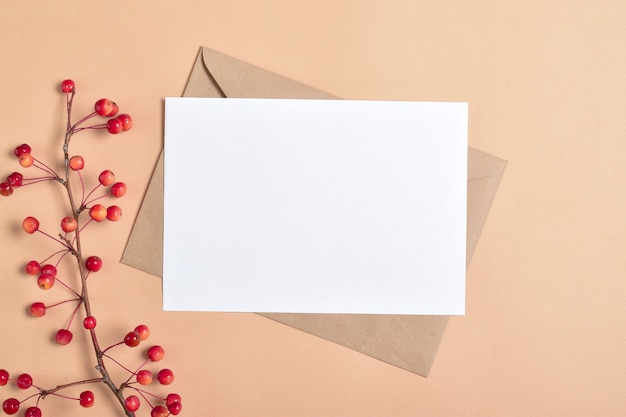 Modèle d'invitation avec une enveloppe sur fond beige avec une branche d'automne d'un pommier. Une note romantique. Mise en page plate, vue de dessus, endroit pour copier. Mise en page plate, vue de dessus, endroit pour copier.