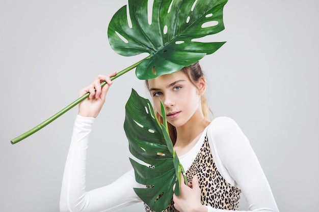 Modèle de jeune belle fille avec portrait de feuilles tropicales sur fond blanc en Studio