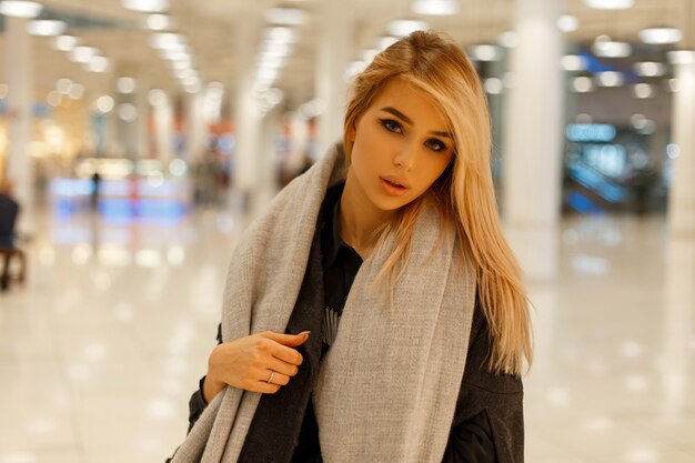 Modèle de jeune femme blonde moderne dans un manteau à la mode chic